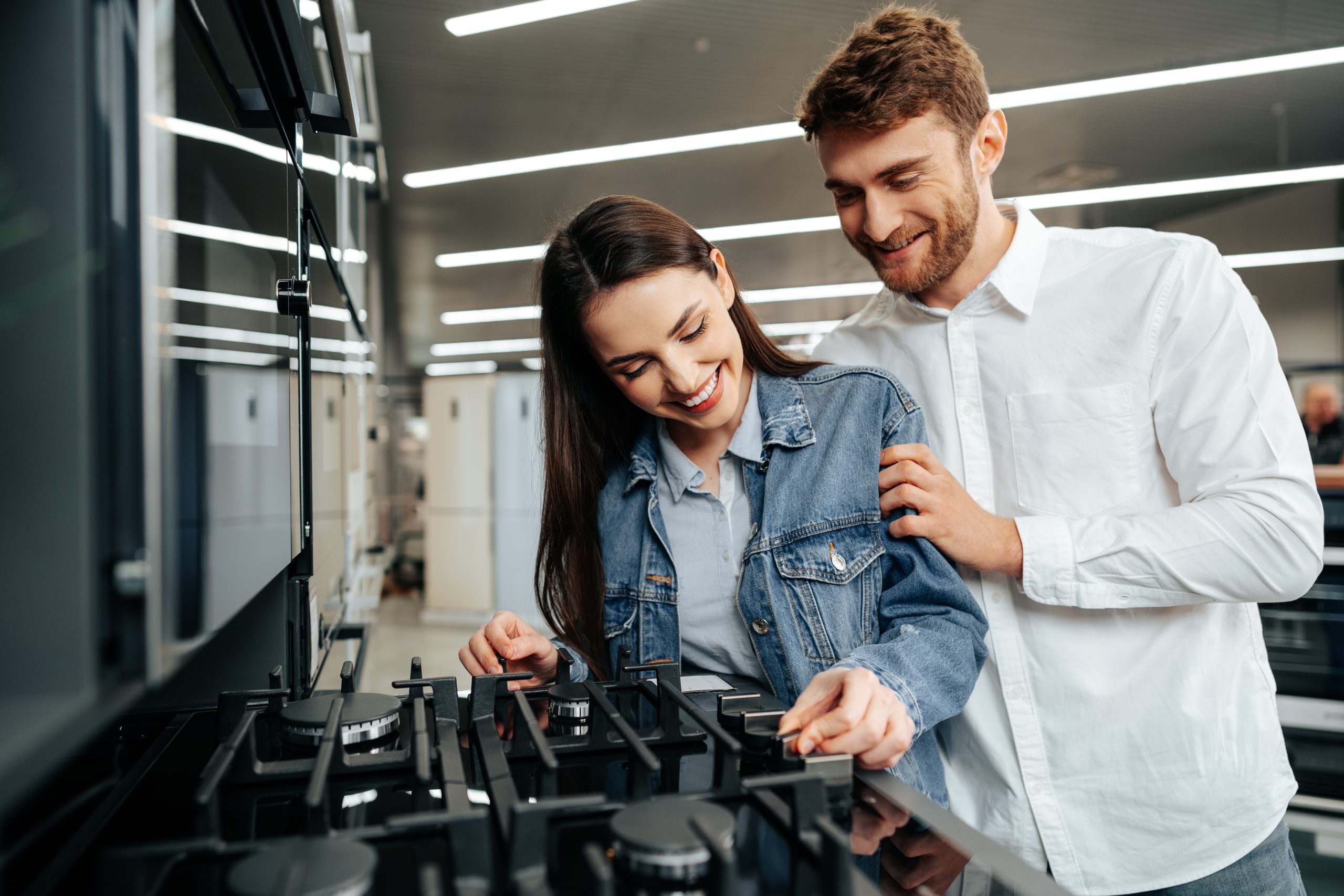 Young couple choosing new gas stove in home appliances store, close up